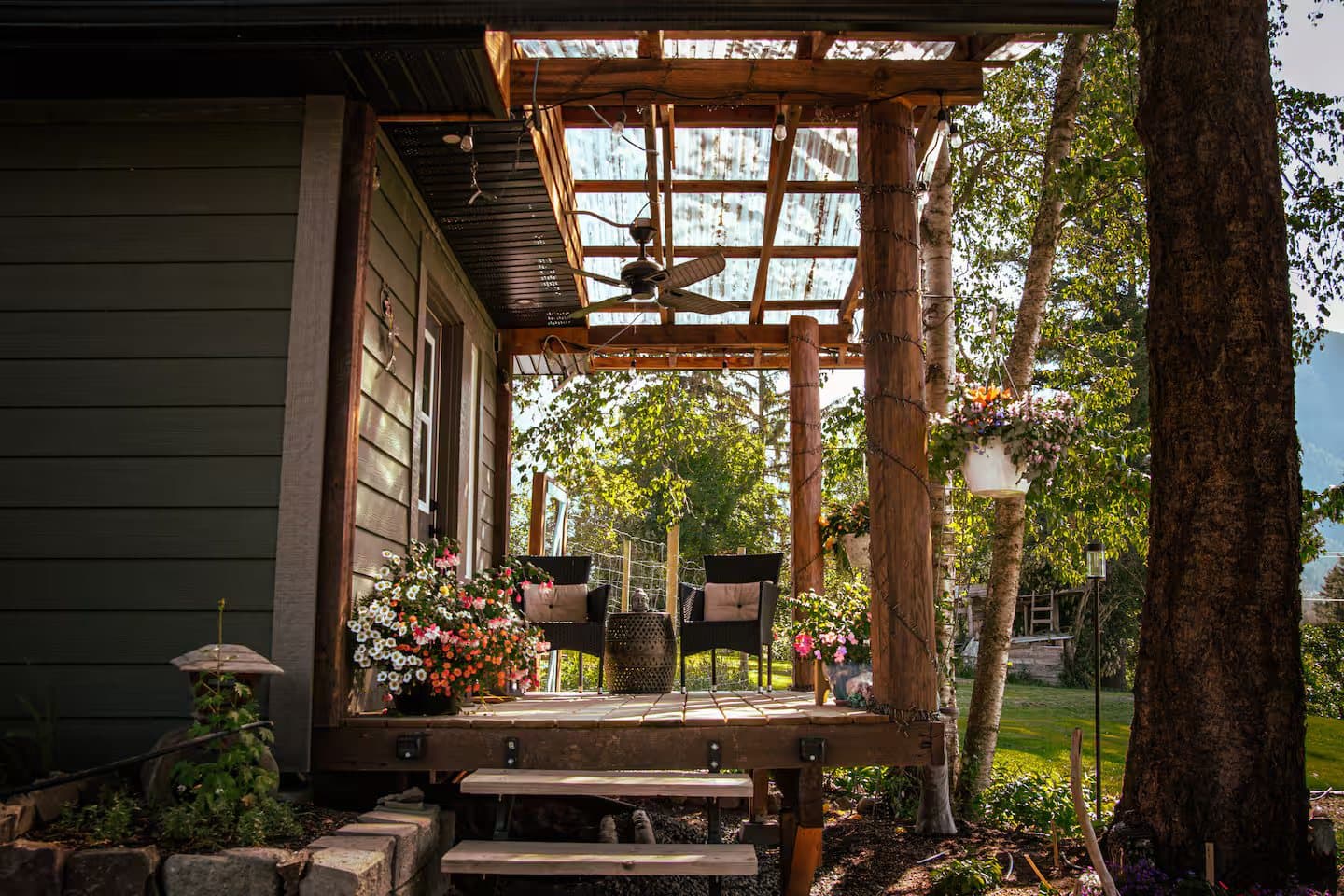 The covered porch at Indigo Oasis — chairs, hanging blooms, and afternoon light through the trellis